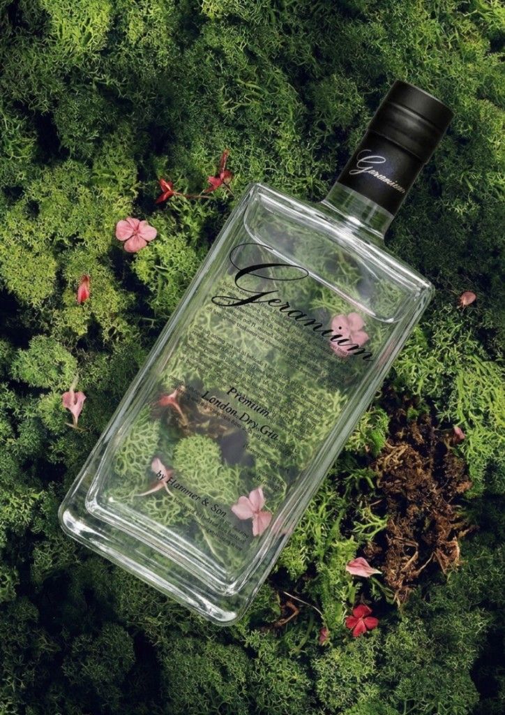 Geranium Gin bottle on a forest bed of moss and geranium flowers.