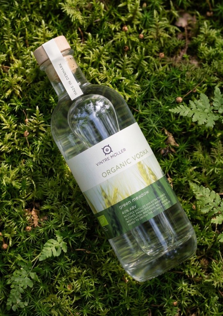 Green Meadow Organic Vodka bottle on a forest bed of moss and ferns.