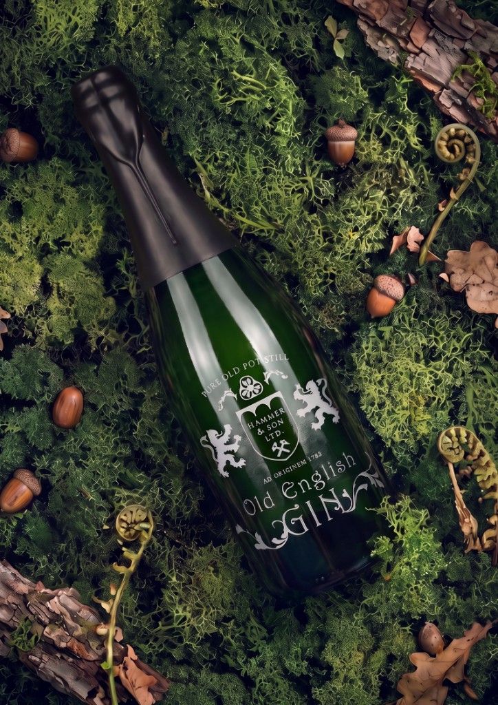 Old English Gin bottle on a forest bed of moss, acorns, and ferns.