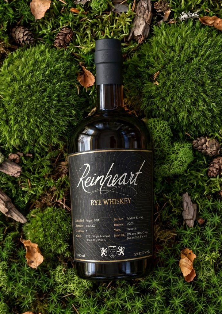 Reinheart Rye Whiskey bottle on a forest bed of moss, pinecones, and fallen leaves.